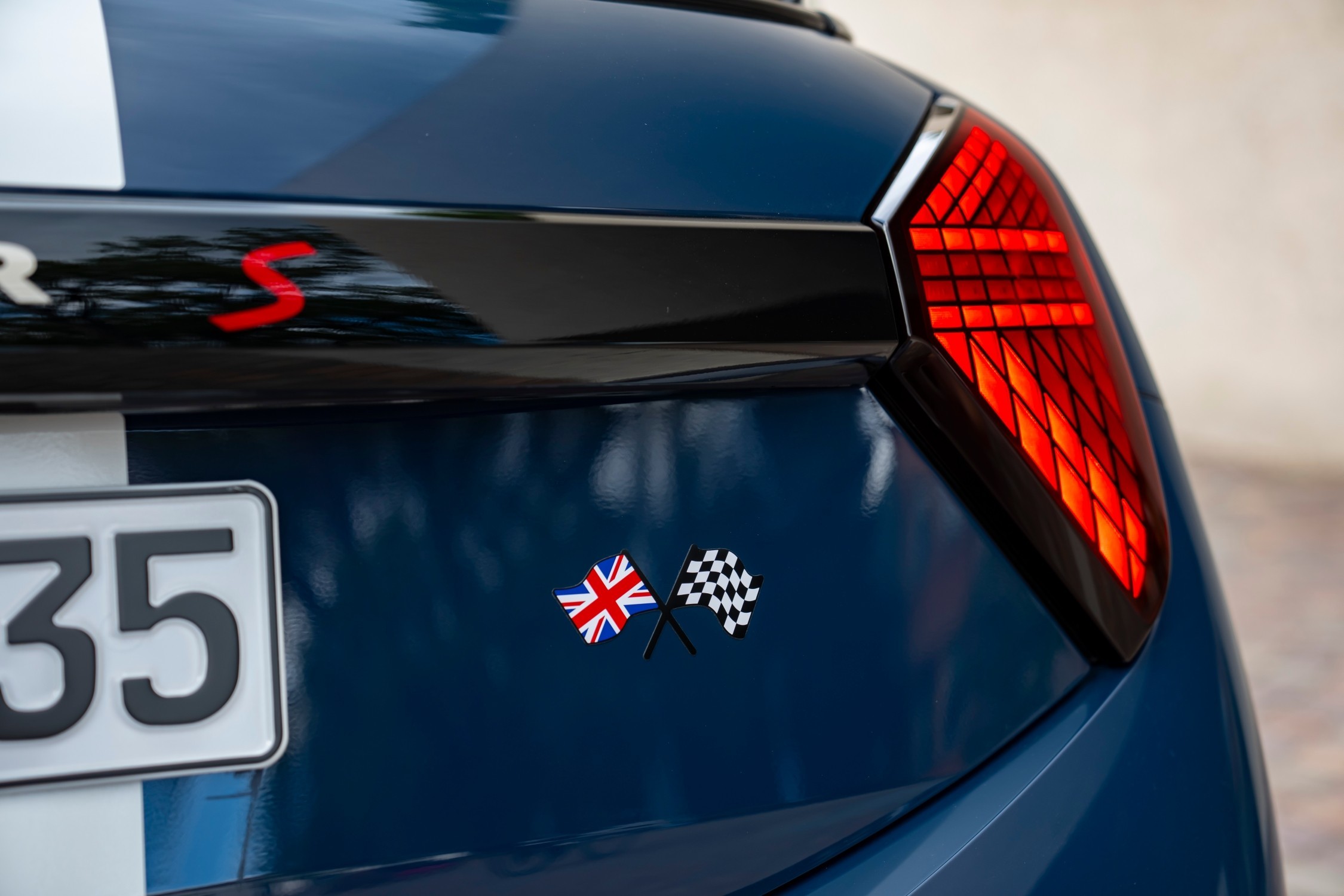 Detalhe da traseira do MINI Cooper Oxford Edition azul, com emblemas Union Jack e bandeira de xadrez junto ao farolim